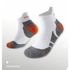 A pair of white performance sports ankle socks with gray and orange accents shown from the side.