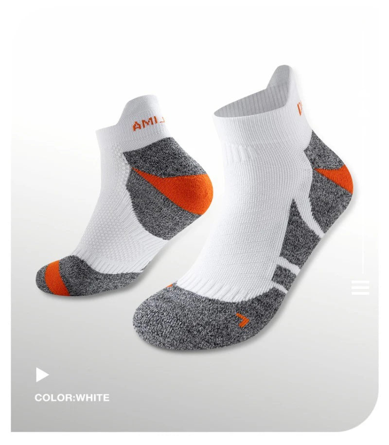 A pair of white performance sports ankle socks with gray and orange accents shown from the side.
