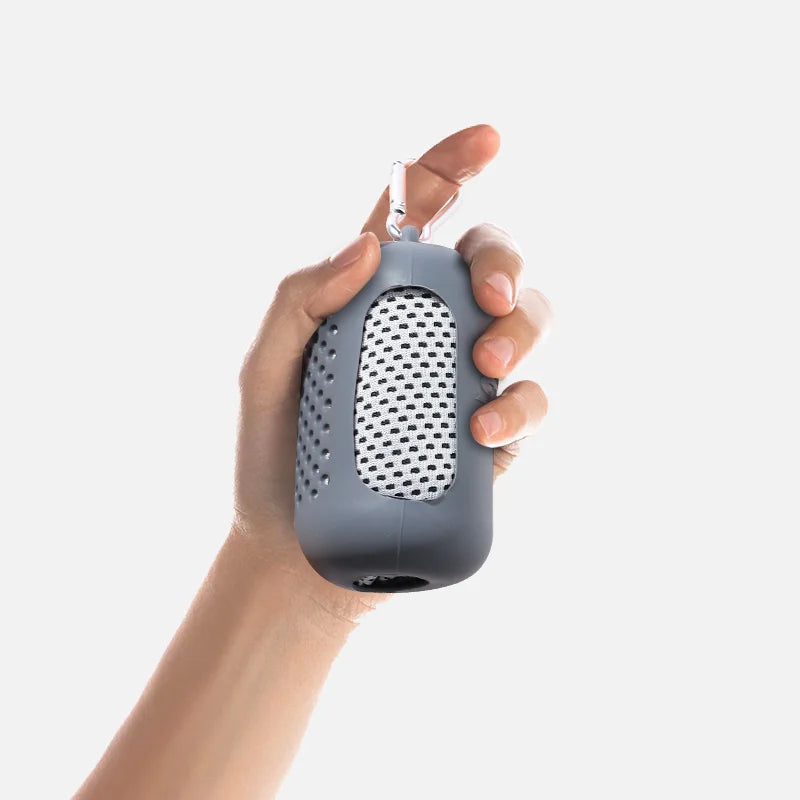 A hand is holding a gray cooling towel with a mesh texture and a silver clip.