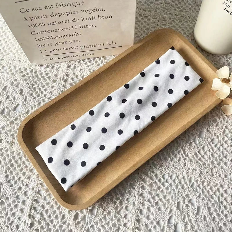 Weißes Stoff-Haarband mit schwarzen Polka Dots auf einem Holztablett