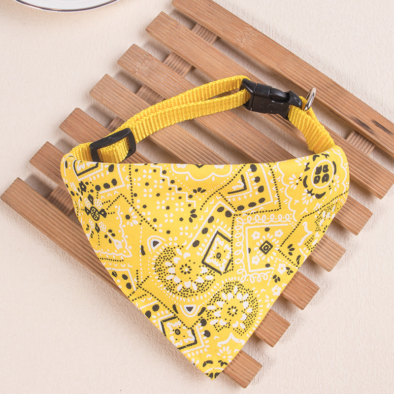 Yellow patterned adjustable pet scarf for dogs and kittens resting on a wooden surface.