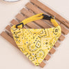 Yellow patterned adjustable pet scarf for dogs and kittens resting on a wooden surface