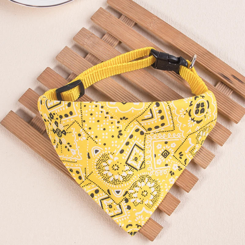 Yellow patterned adjustable pet scarf for dogs and kittens resting on a wooden surface