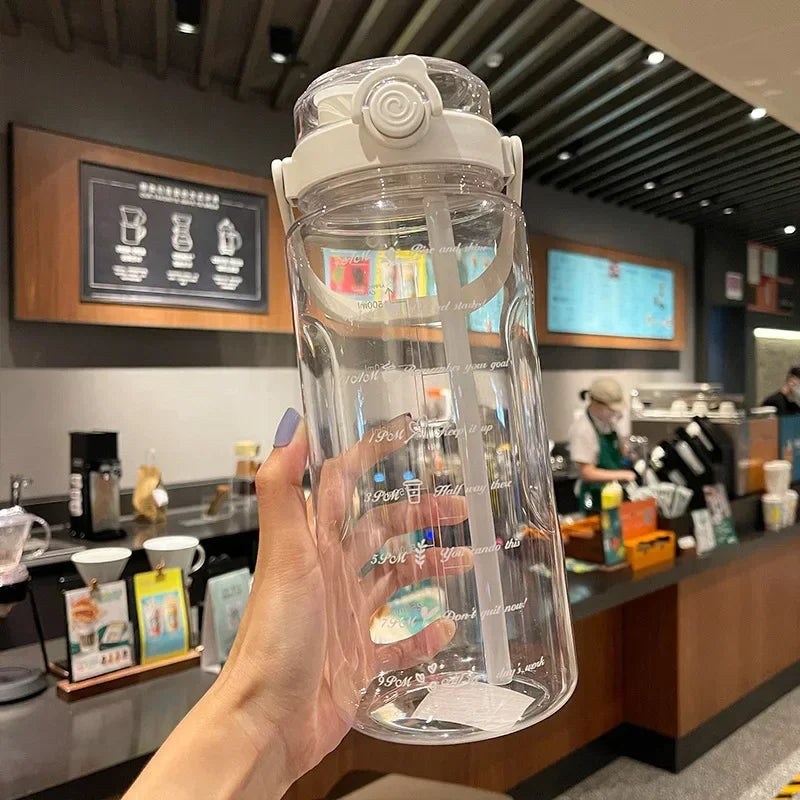 A hand holds a clear plastic water bottle with a straw and time scale markings in a retail setting.