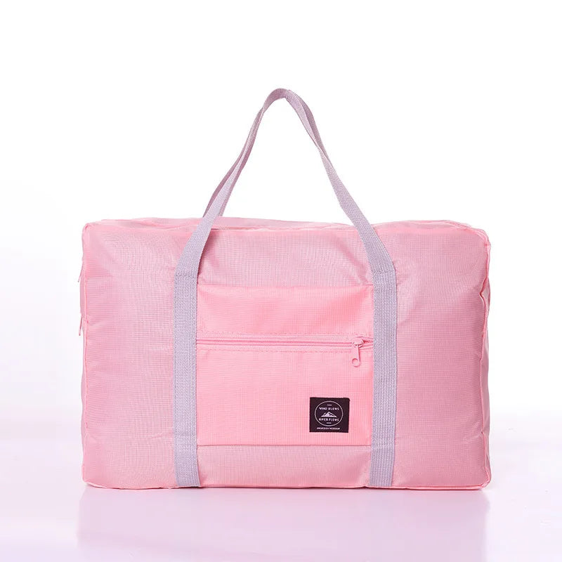A pink foldable travel duffel bag with a shoulder strap is shown against a white background.