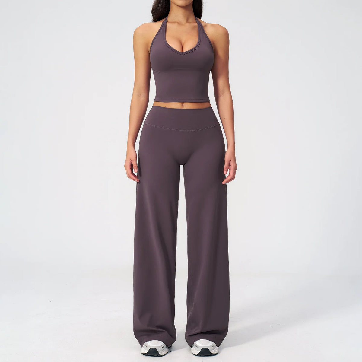 A woman wearing a dark purple women's premium fitness tracksuit top and matching pants.