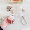 A hand holds a pink quartz protective case for AirPods Pro next to various natural stone and leopard print accessories.