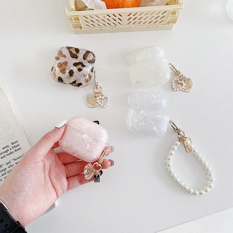 A hand holds a pink quartz protective case for AirPods Pro next to various natural stone and leopard print accessories.