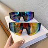 A pair of black cycling sunglasses with iridescent blue and purple lenses resting on a white book.