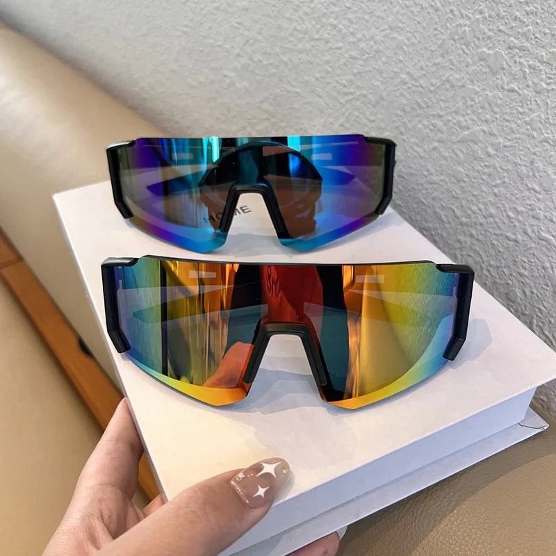 A pair of black cycling sunglasses with iridescent blue and purple lenses resting on a white book.