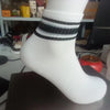A close-up of a white sock with black horizontal stripes near the cuff.