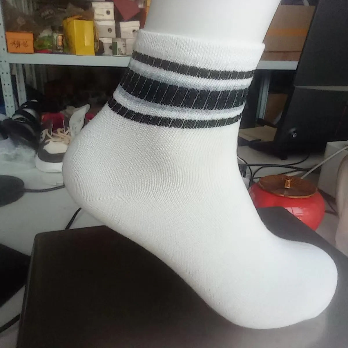 A close-up of a white sock with black horizontal stripes near the cuff.