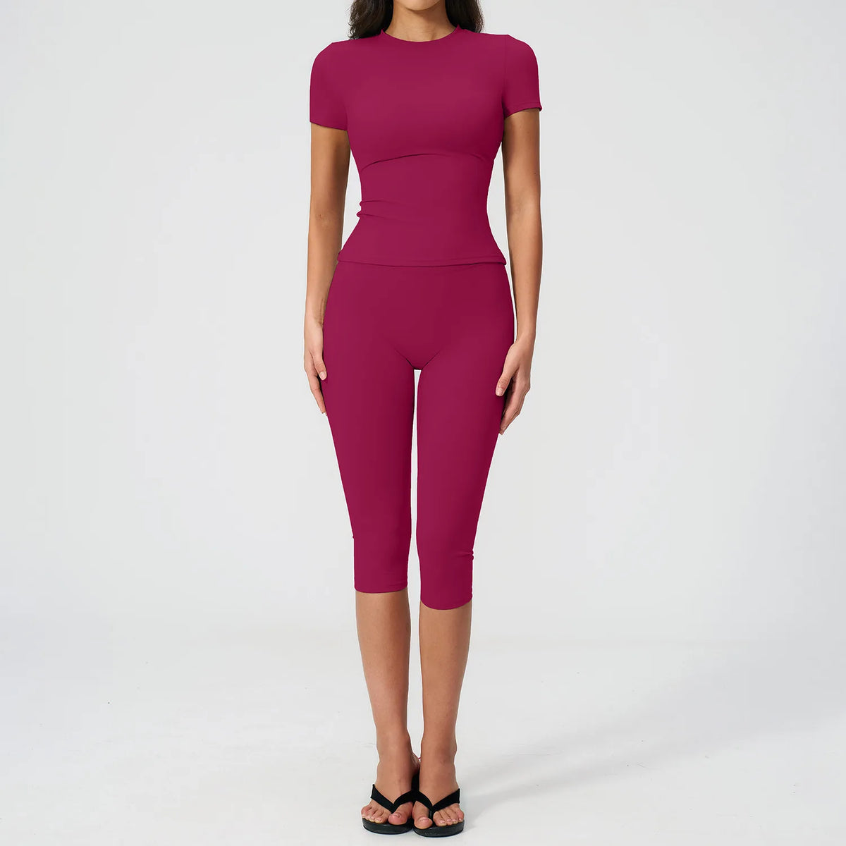 A woman wearing a magenta women's premium fitness tracksuit top and leggings.