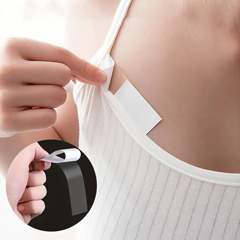 A hand is applying a piece of white double-sided fashion adhesive tape to the skin on a person's shoulder.