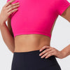 A woman wearing a bright pink crop top and dark athletic leggings.