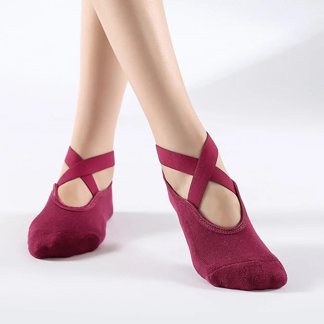 A pair of deep magenta silicone yoga and pilates socks worn on a model's feet.