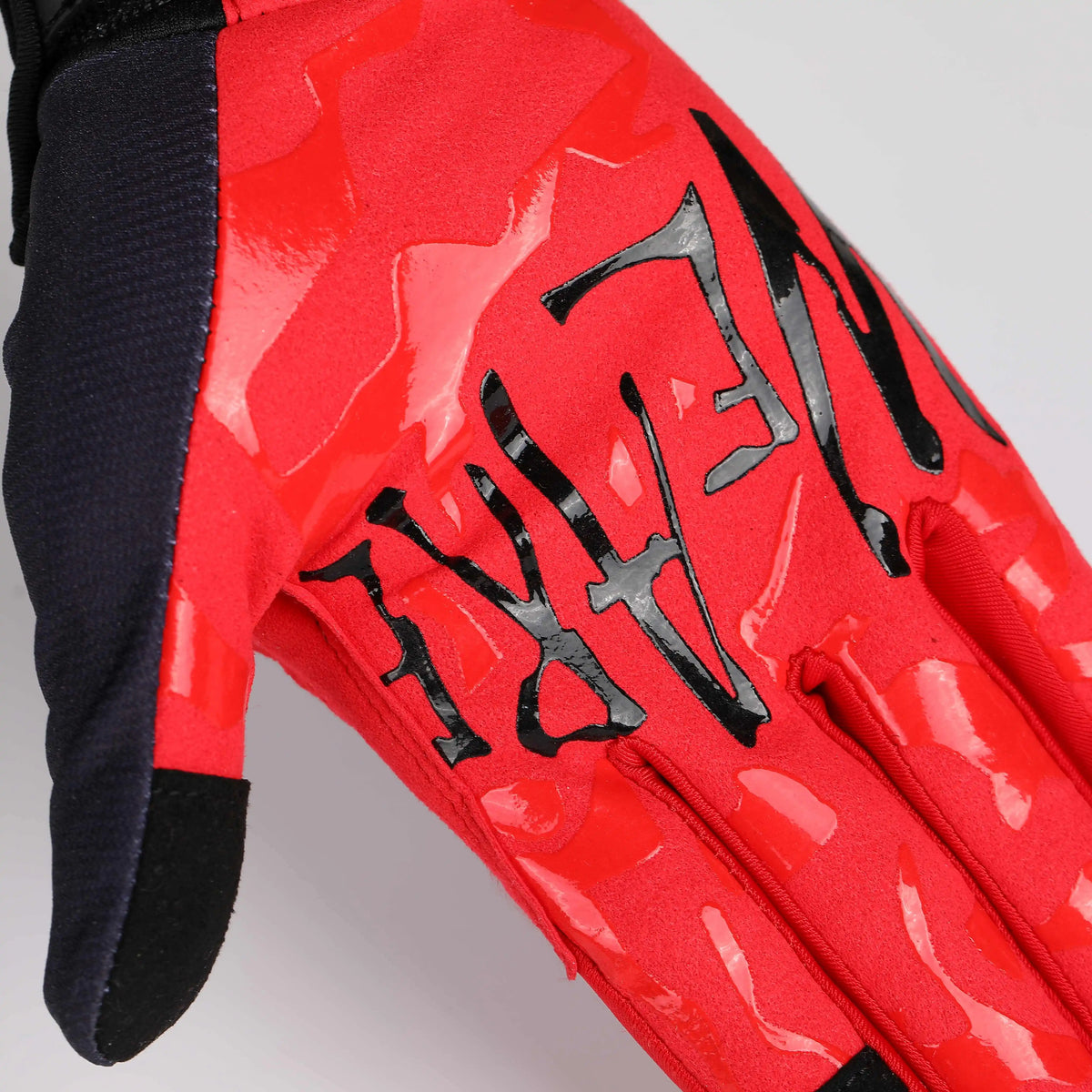 A close-up of a red camouflage cycling riding glove.