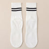 A pair of white grip socks with black stripes for yoga and barre