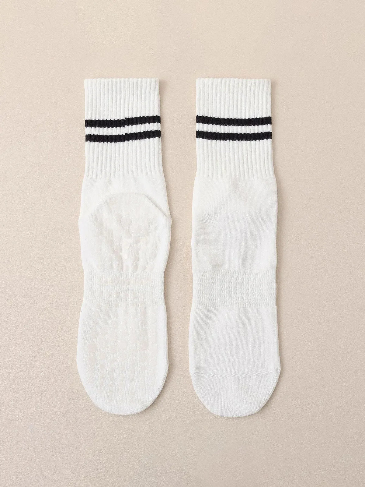 A pair of white grip socks with black stripes for yoga and barre