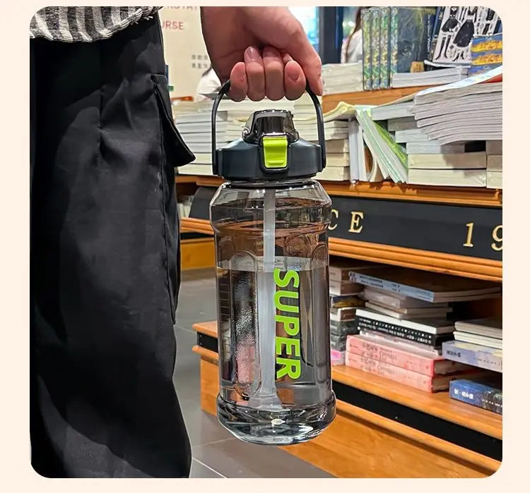 A hand holds a clear insulated sports water bottle with a yellow cap and straw, placed on a wooden shelf.
