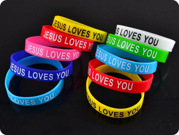 A stack of silicone religious bangle bracelets in various colors, each engraved with the phrase Jesus loves you.