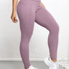 A woman wearing mauve high-waisted sports leggings and white sneakers.