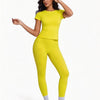 Una mujer modela un conjunto de yoga sin costuras, de cintura alta y amarillo brillante, con top de manga corta y leggings.