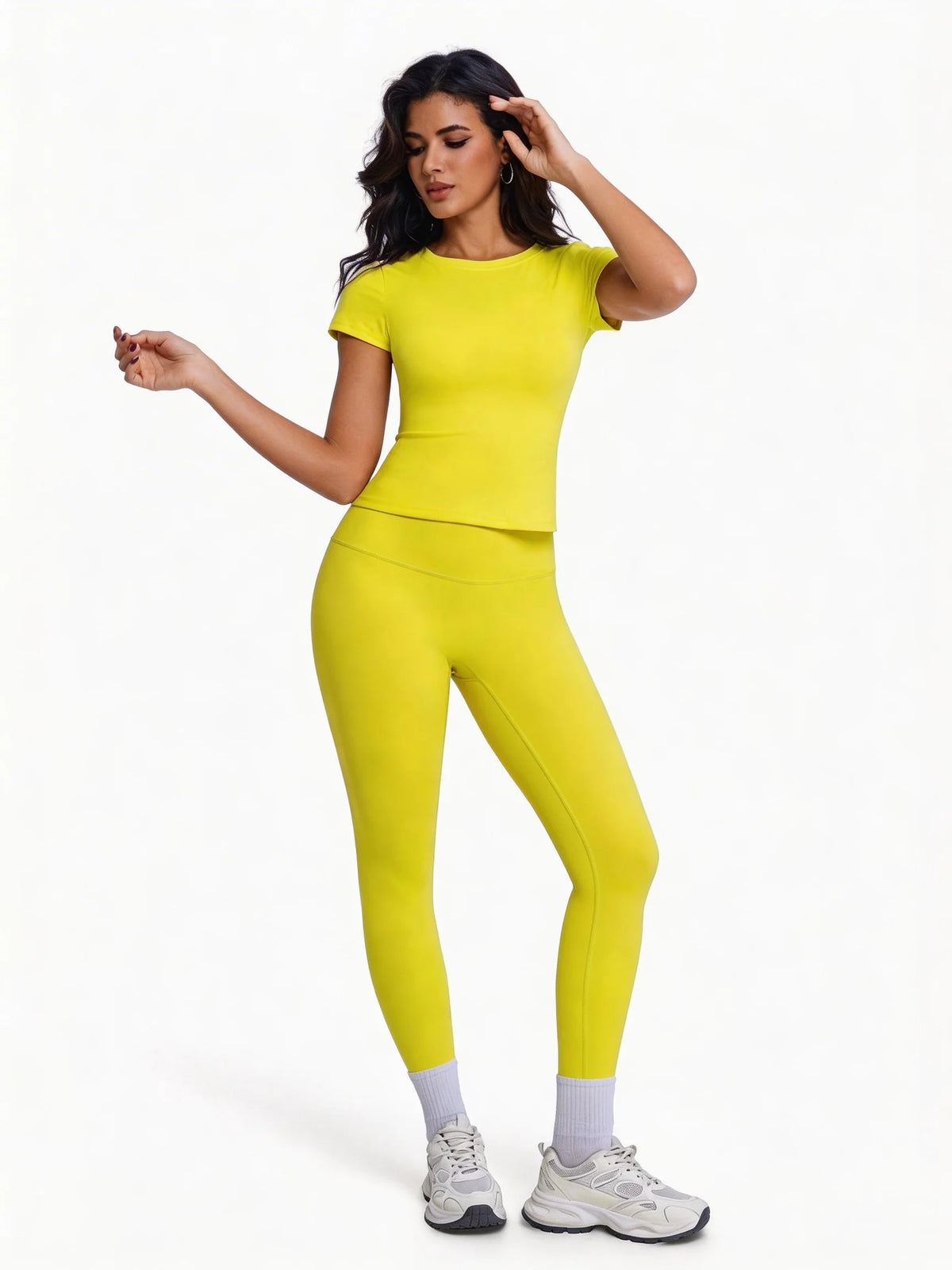Una mujer modela un conjunto de yoga sin costuras, de cintura alta y amarillo brillante, con top de manga corta y leggings.