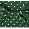 A dark green fabric headband with light polka dots tied in a bow.