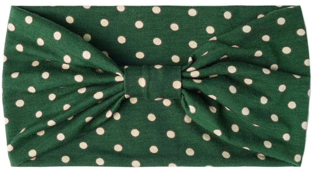 A dark green fabric headband with light polka dots tied in a bow.