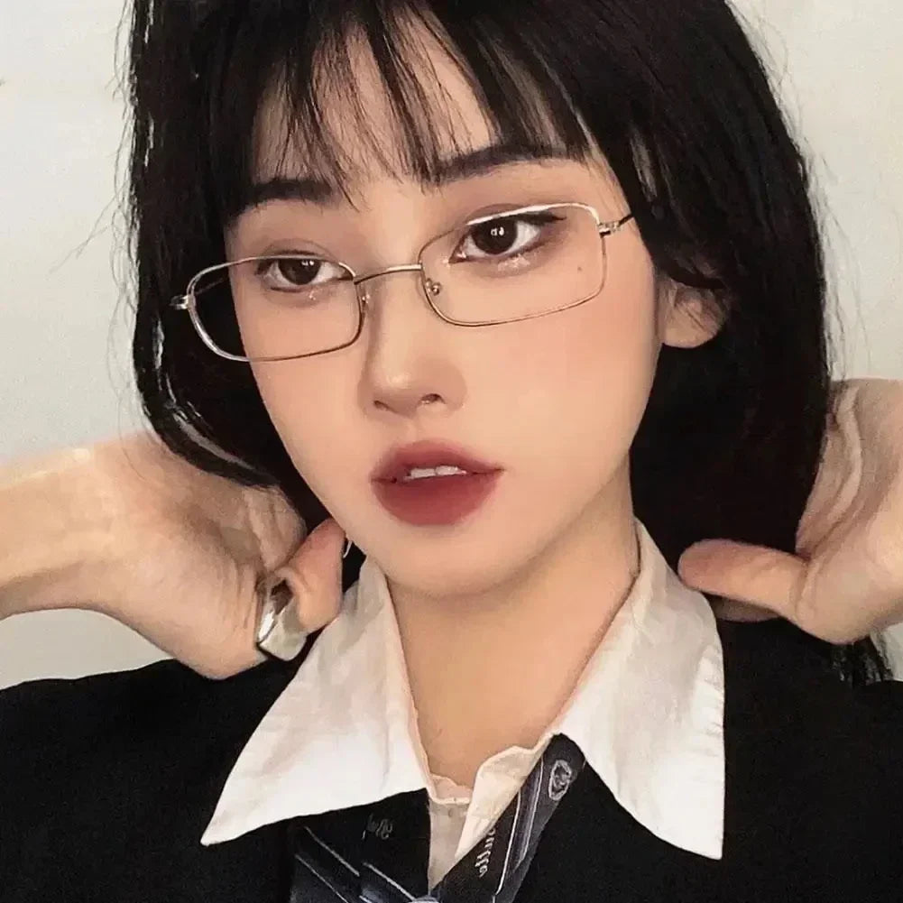 A close-up photo of a person wearing retro square frame eyeglasses against a light background.