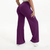 A person is modeling purple NCLAGEN SoftMotion straight leg yoga pants in a full-length shot.