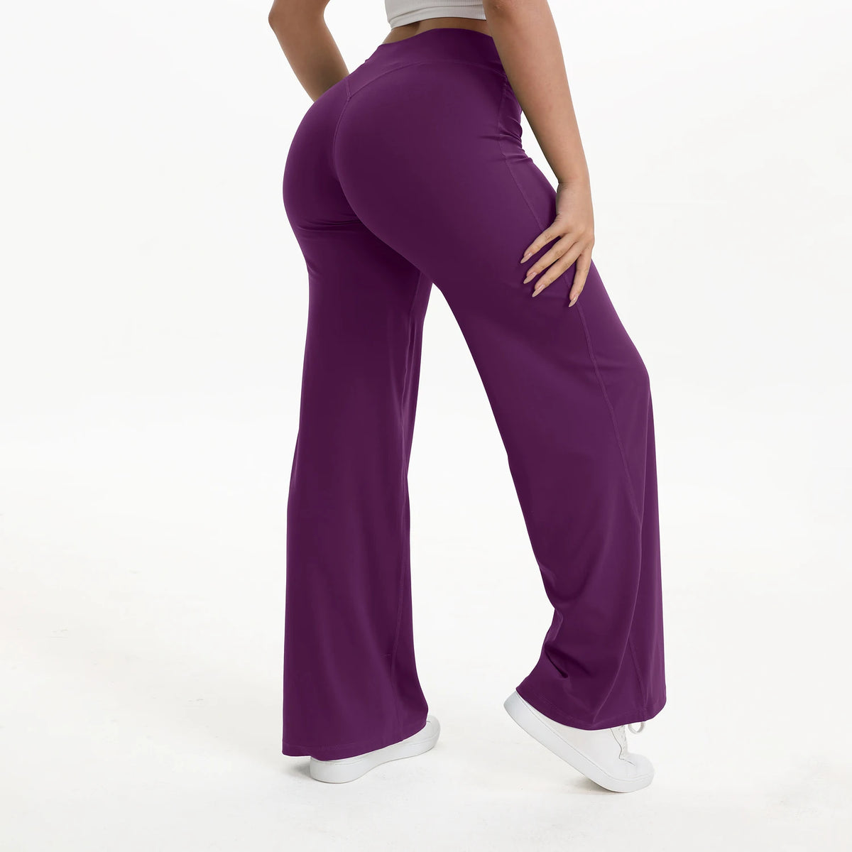 A person is modeling purple NCLAGEN SoftMotion straight leg yoga pants in a full-length shot.