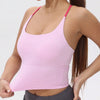 A woman wearing a pink women's athletic crisscross tank top and gray athletic pants.