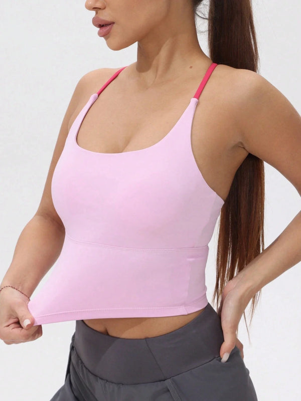 Eine Frau trägt ein pinkes sportliches Kreuz-Crop-Top und graue Sportpants.