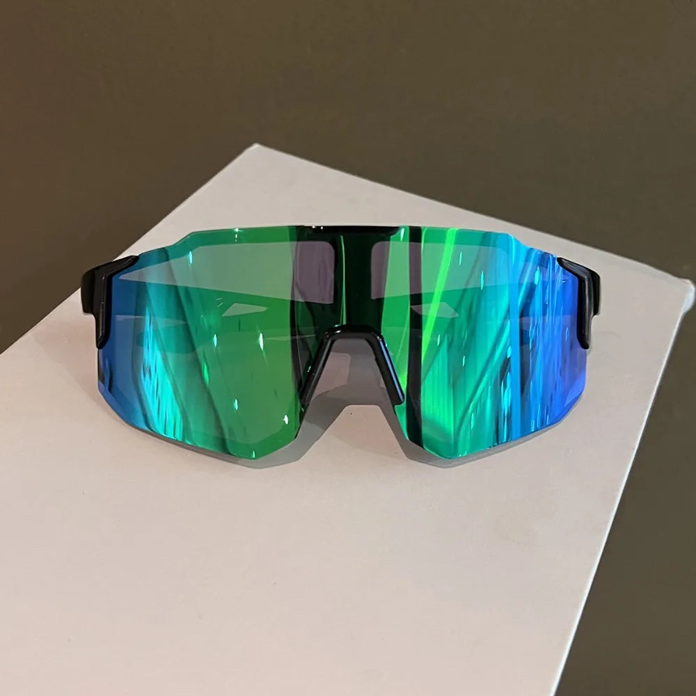 A pair of green and blue mirrored sport cycling and skiing goggles resting on a white surface.