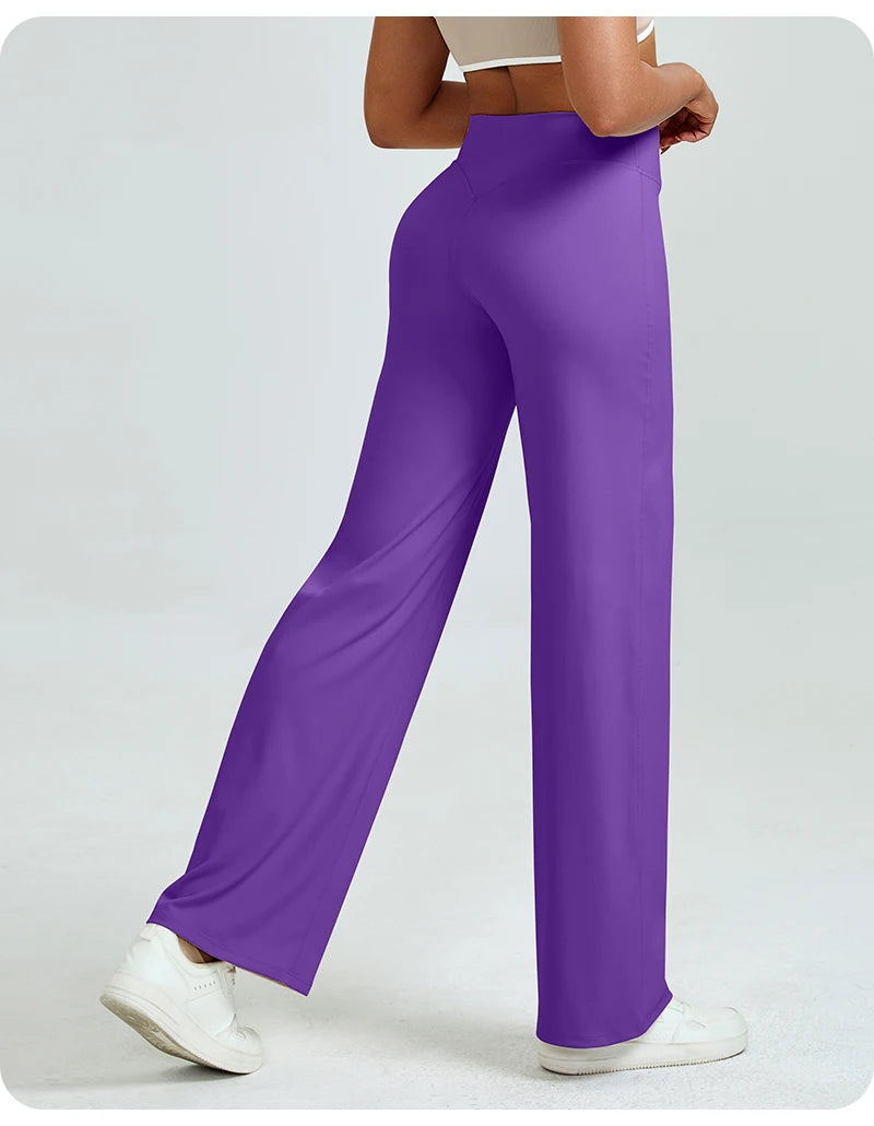 A woman is modeling high waisted purple yoga pants with a white top and white sneakers.