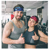 A muscular man and woman posing in a gym setting, both wearing sports headbands.