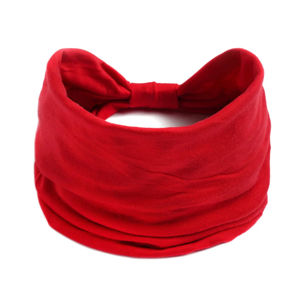 Un foulard en coton bohème rouge vif noué en nœud.