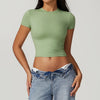 Una modelo vistiendo una camiseta deportiva de yoga y fitness verde salvia y jeans azules.