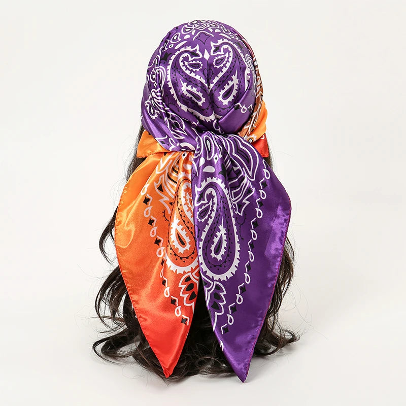 A purple and orange satin square scarf tied around dark hair