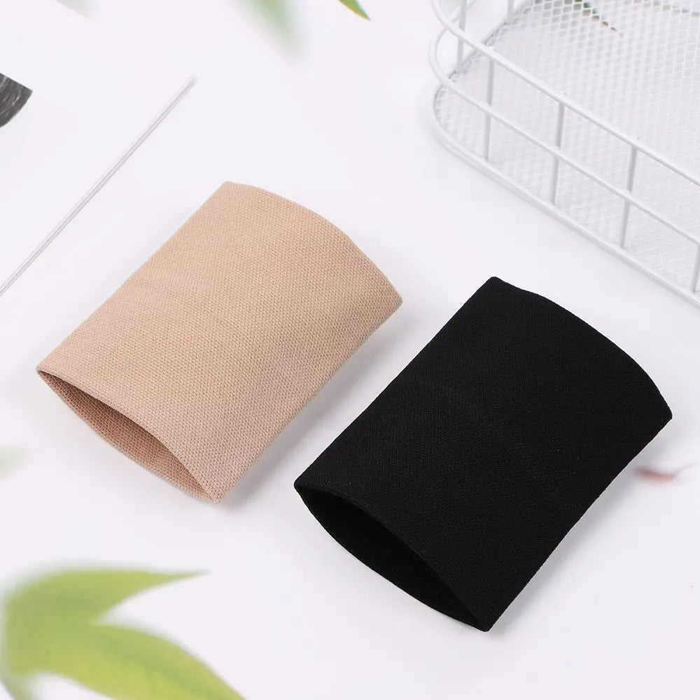 Manche de compression beige et noir pour le poignet, posé sur une surface blanche.