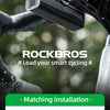 A black Rockbros GPS cycling computer and speedometer mounted on a bicycle handlebar.
