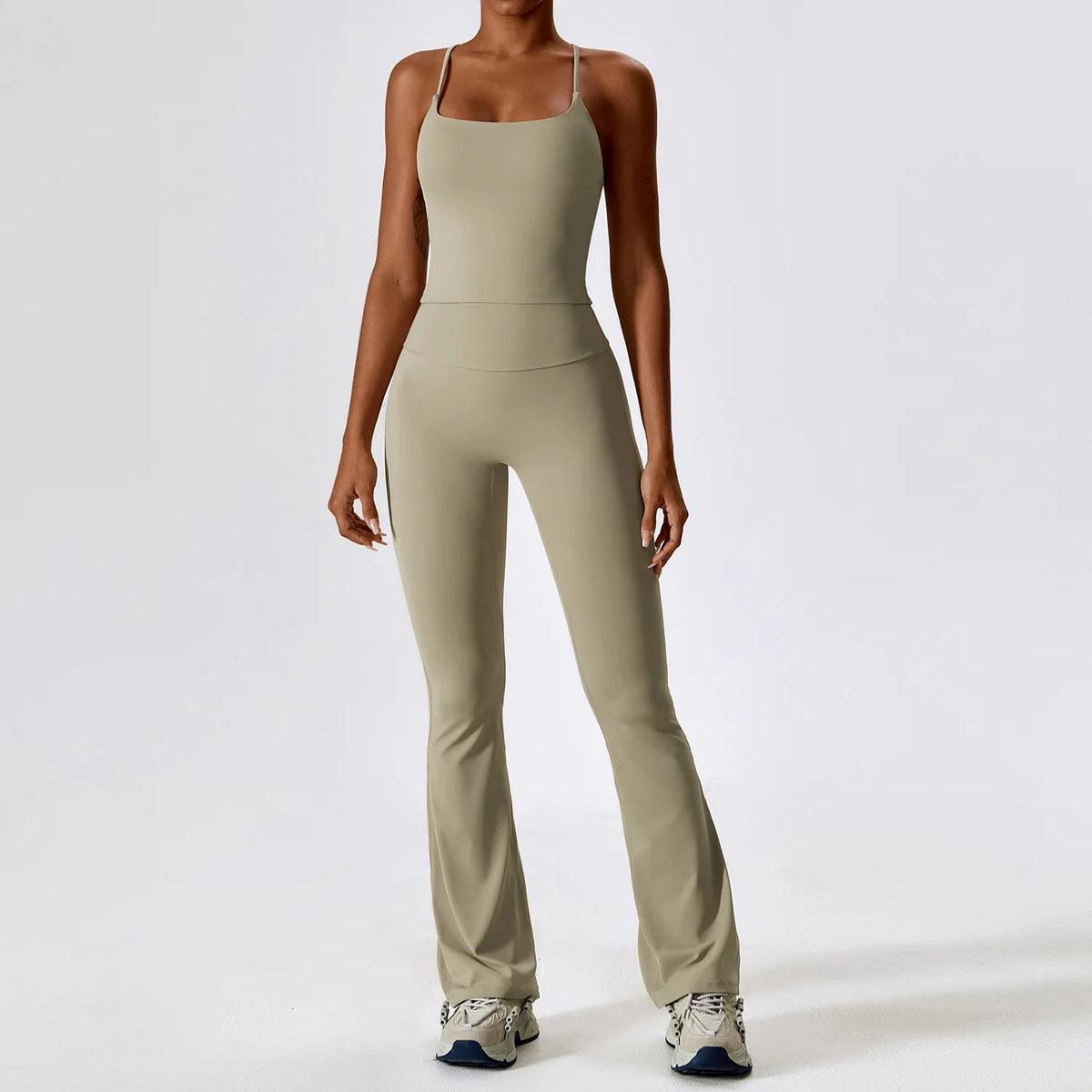 A woman wearing a beige women's performance tracksuit set, including a tank top and matching pants.