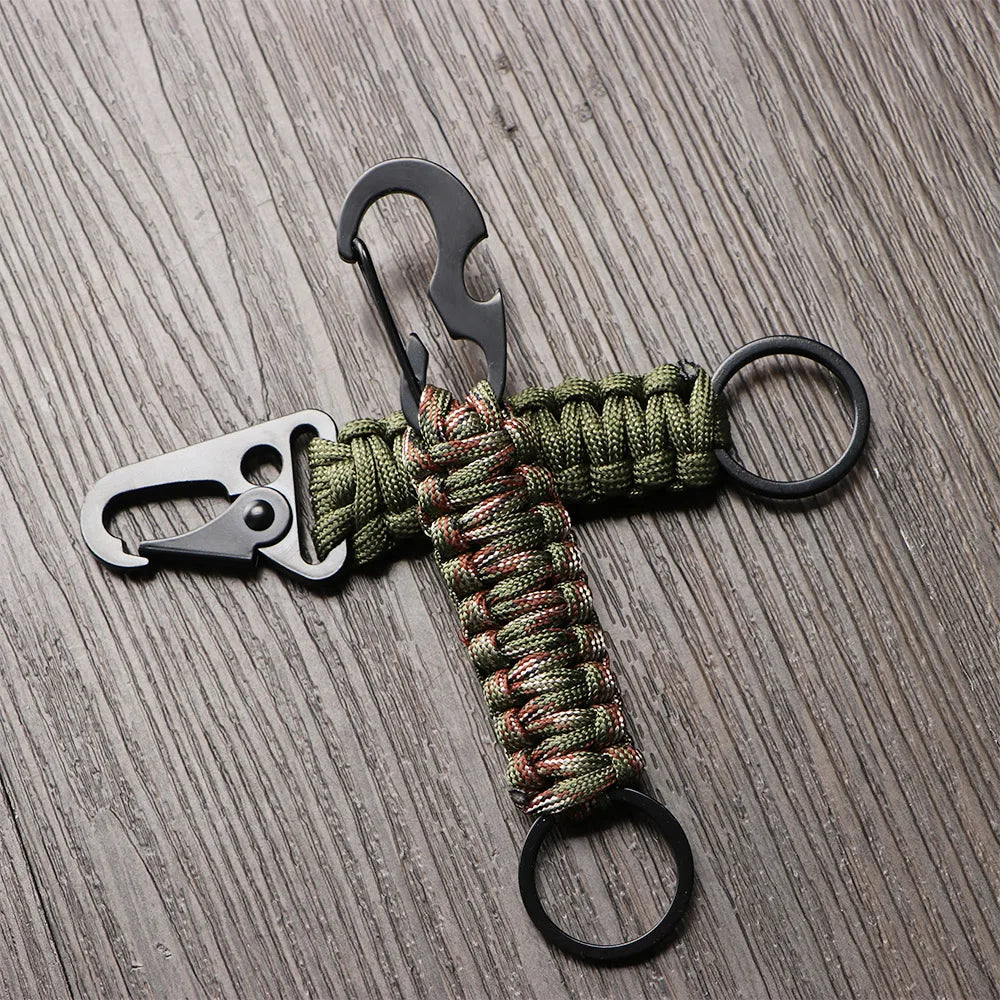 A multi-tool keychain featuring a silver-colored tool and a green braided cord on a dark wooden surface.