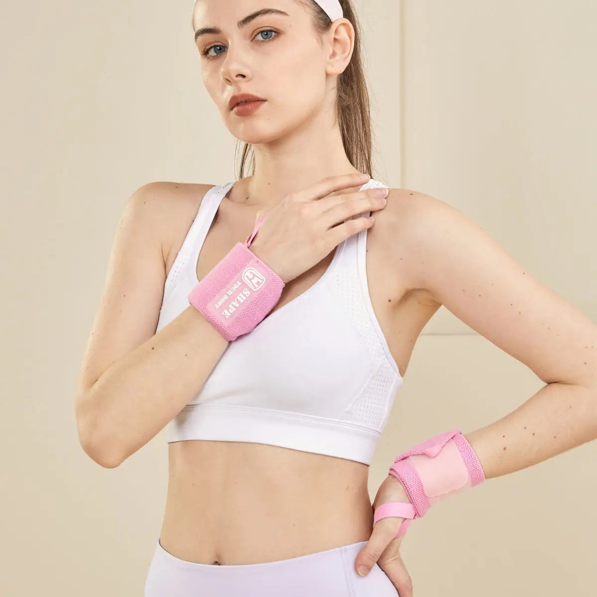 A woman wearing a white sports bra and pink wrist guard bandages for fitness.