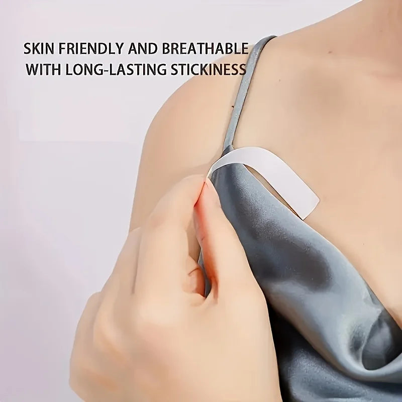 A hand applies a piece of clear double-sided fashion adhesive tape to the skin on a person's shoulder.