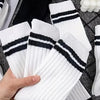 A hand holds a stack of white and black striped men's socks on a dark textured surface.