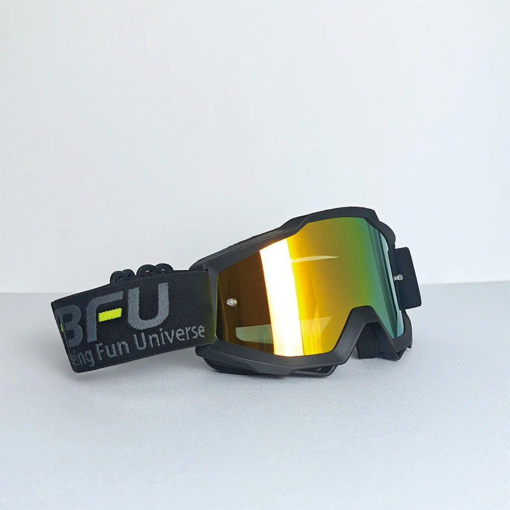 A pair of black sport-grade skiing goggles with yellow-tinted lenses resting on a white surface.