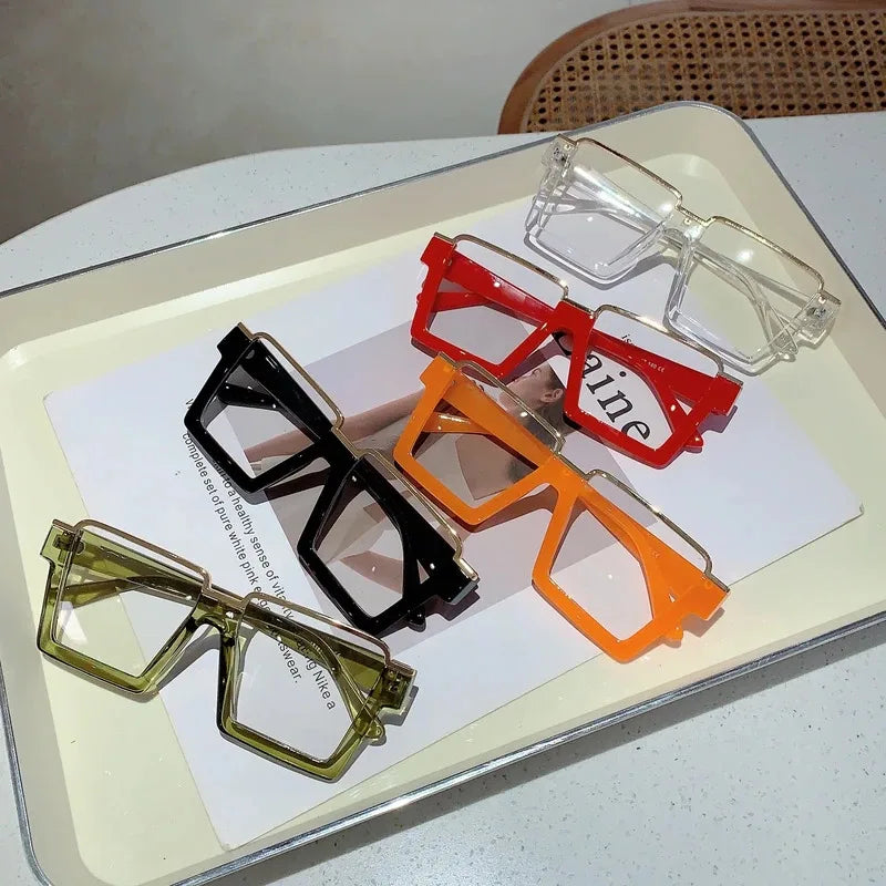 A collection of oversized square semi-rim metal eyeglasses in various colors including clear, red, orange, and olive green.